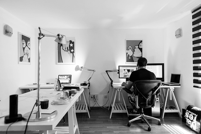 Professional headshot of male content editor with glasses at editorial desk with monitors